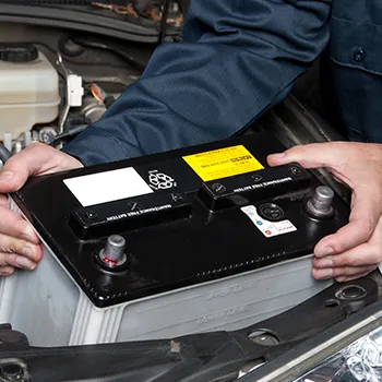 Mechanic installing car battery under hood.